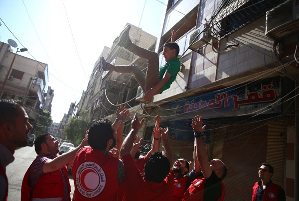 Members of the Syrian Arab Red Crescent throw a young boy in the air as they celebrate the first day of Eid Al Fitr in Douma, on July 6 (AFP photo)